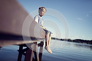 Boy with legs dangling from pier