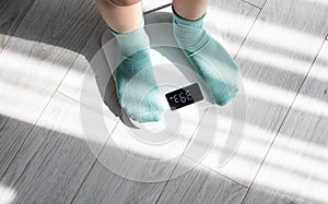 Boy legs stepping on floor scales at home. Weight control concept