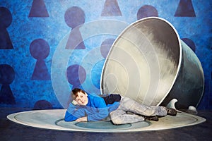 Boy lies on saucer near big photo