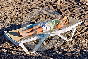 Boy lies on sunbed on the shore