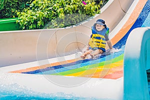 A boy in a life jacket slides down from a slide in a water park