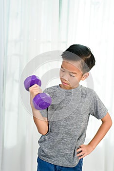 Boy lift dumbell by his strong arm