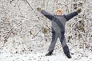 Boy lifted hands upwards in wood in winter photo