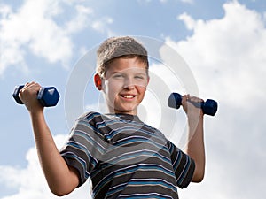 Boy lifting dumbbells outdoors