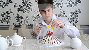 Boy lights candles on the cake with a lighter