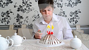 Boy lights candles on the cake with a lighter