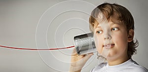 Boy listen Tin Can Phone play with retro toy. Isolated on grey Background