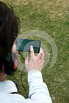 Boy is listening music with headphone and using smartphone