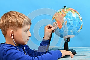 Boy listening to the globe through a stethoscope. The concept of a virus affecting the entire planet