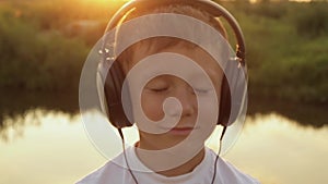 Boy listening to music in headphones on a nature, summer, sunset