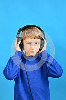 The boy listens attentively to various sounds through headphones and holds the speakers with his hands