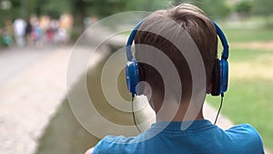 The boy listens to music on headphones