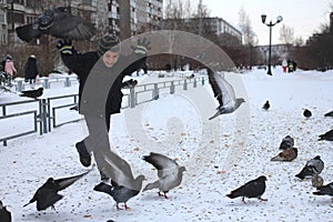 Little baby boy rides in the Park of birds pigeons in winter laughs fun emotions