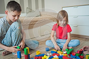 A boy and a little girl in a children`s room play in colorful cubes