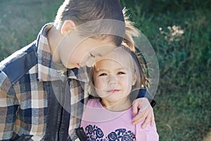 Boy and little girl hugging portrait. Happy smiling children outdoors at sunny day.Friendship siblings. Brother embrace sister