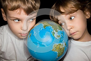 Boy and little girl steadfastly looking at globe
