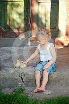 Boy with little yellow duckling in summer village