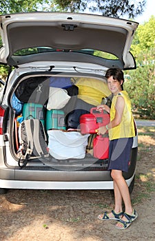 Boy loads the luggage in the trunk of the car