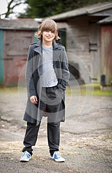 Boy in Long Coat Standing in a Farm Yard