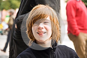 Boy with long red hair pokes his tongue as a joke