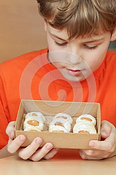 Boy look at open box of corrugated cardboard with cookies