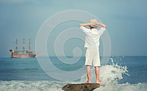 Boy looking on big old ship on the sea