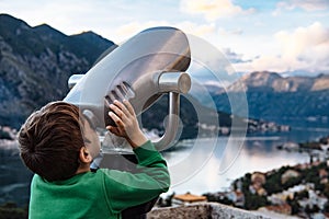 Boy looking through binocular at the city of Kotor, Montenegro