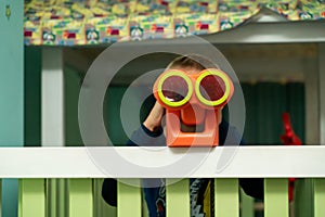 Boy looking through binoculars in the children`s room