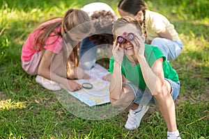 Boy looking through binoculars and friends studying map
