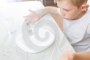 Boy is looking at an empty plate