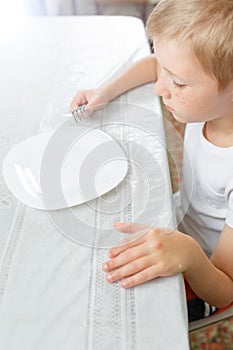 Boy is looking at an empty plate