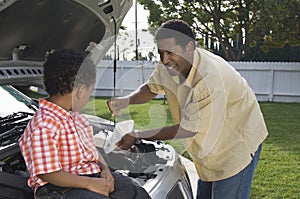 Boy Looking At Father Checking Engine Oil