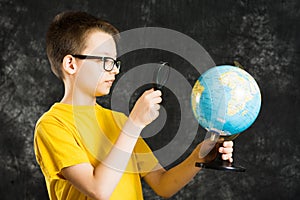 Boy looking at globe with magnifying glass