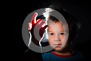 Boy looking with great curiosity at his hand in a ray of light photo