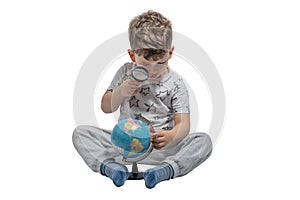 Boy looking through magnifying glass at globe, isolated on white background. School, education concept