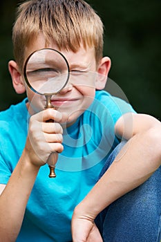 Boy Looking Through Magnifying Glass With Magnified Eye