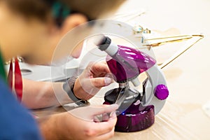 Boy looking through a purple microscope at a bird feather at a children`s science event
