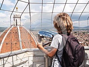 Boy looking through a sightseeing binoculars the Dome of Basilic