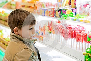 A boy is looking at sweets and sweets on a shop window in a shopping center