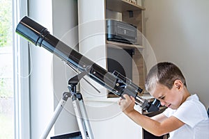 A boy looking through a telescope indoors