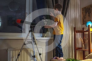Boy is looking through a telescope at the night starry sky. Children`s passion for space exploration