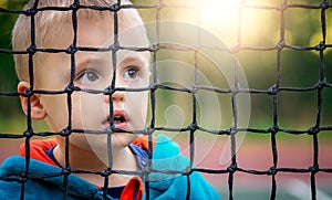 Boy looking through the tennis net