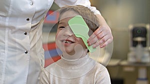 Boy looking at vision test with one eye covered with occluder