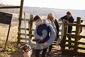 Boy looks down at pet dog during family walk in countryside