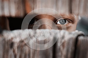 Boy looks through the gap in the fence. The concept of voyeurism, curiosity, Stalker, surveillance and security photo