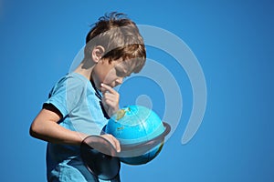 Boy looks on globe against sky