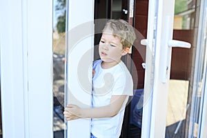 The boy looks out of the house