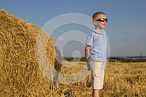 Boy looks at sunset,in a field of mowed wheat the boy looks at the sun in black glasses