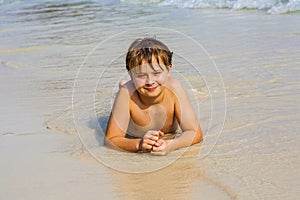 Boy is lying at the beach and enjoys the water and looking self