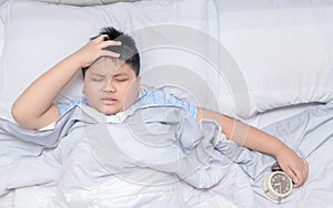 Boy lying in bed and suffering from headache